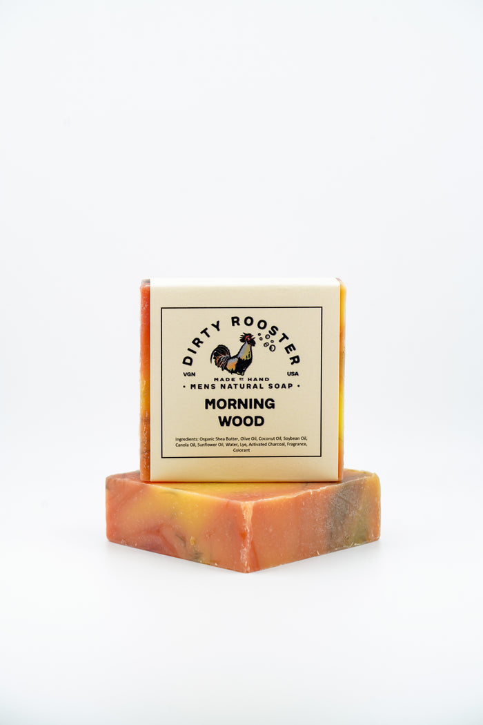 Morning Wood handmade natural soap bar for men, wrapped, standing on an unwrapped orange, red and yellow swirled bar