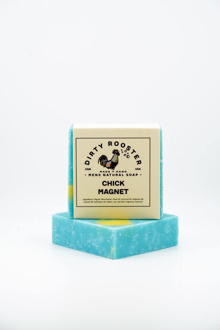 Chick Magnet handmade natural soap bar for men, wrapped, standing on an unwrapped light blue bar