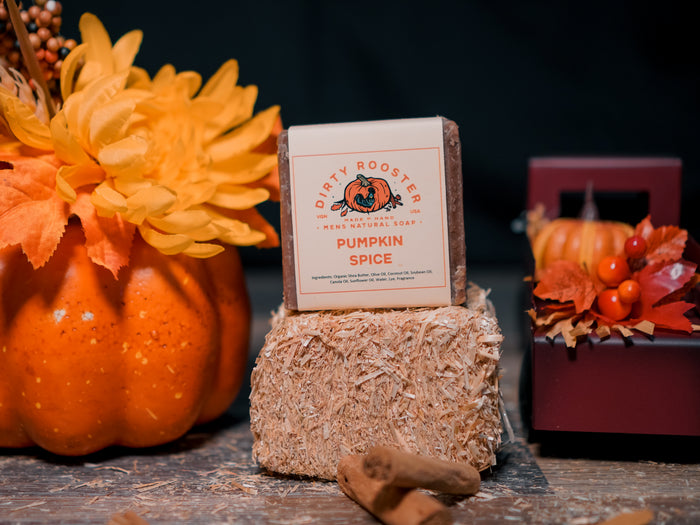 Pumpkin Spice men's natural soap bar on a mini hay bale beside an orange pumpkin