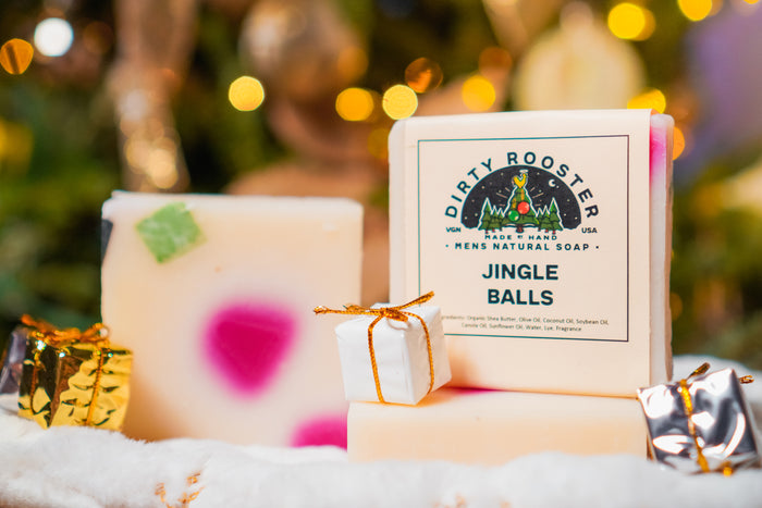 Jingle Balls holiday soap bar for men beside an unwrapped cream bar with pink and green accents, with small gift boxes
